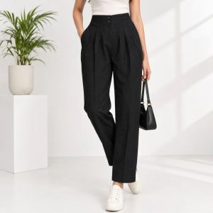 Full view of stylish black high-waist pleated trousers worn by model with white sneakers and handbag